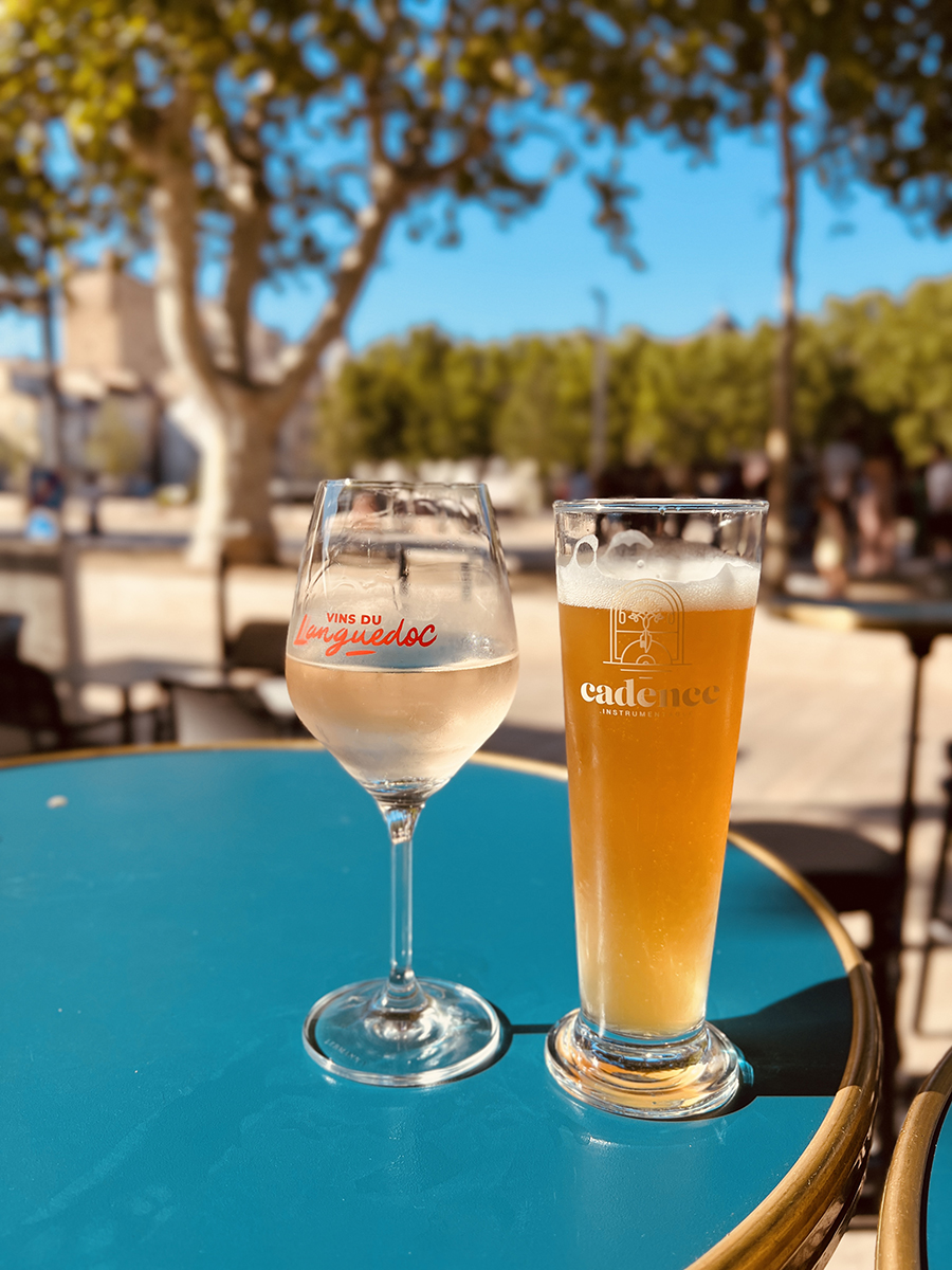 Glass of white wine and fresh beer on a sunny patio table in Narbonne in the South of France — savoring relaxed moments and French outdoor dining culture