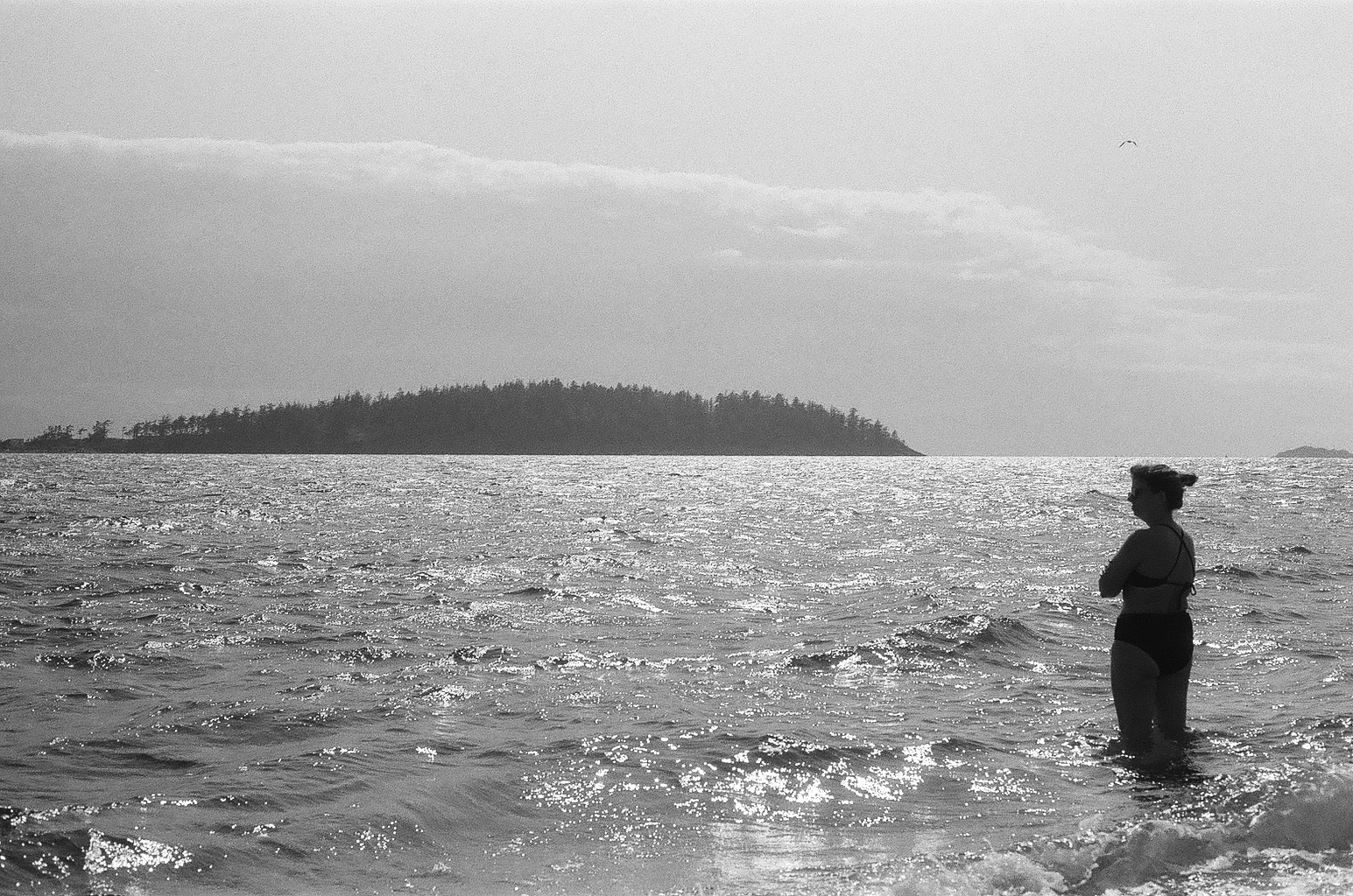 black and white film shot of the silhouette of a woman standing in the ocean